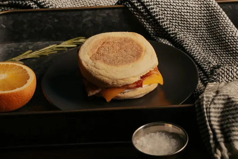 An English muffin breakfast sandwich with egg, bacon and melted cheese