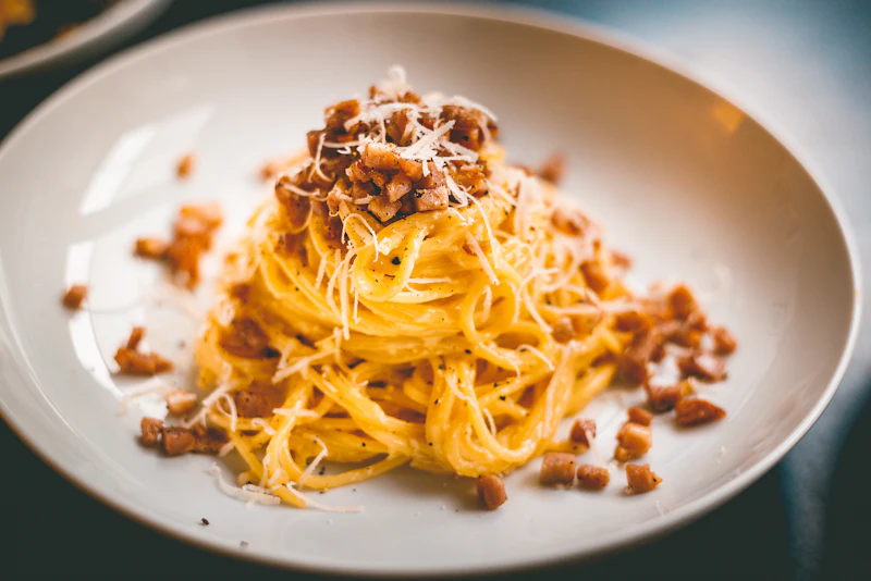 A plate of spaghetti carbonara with crisp pieces of guanciale