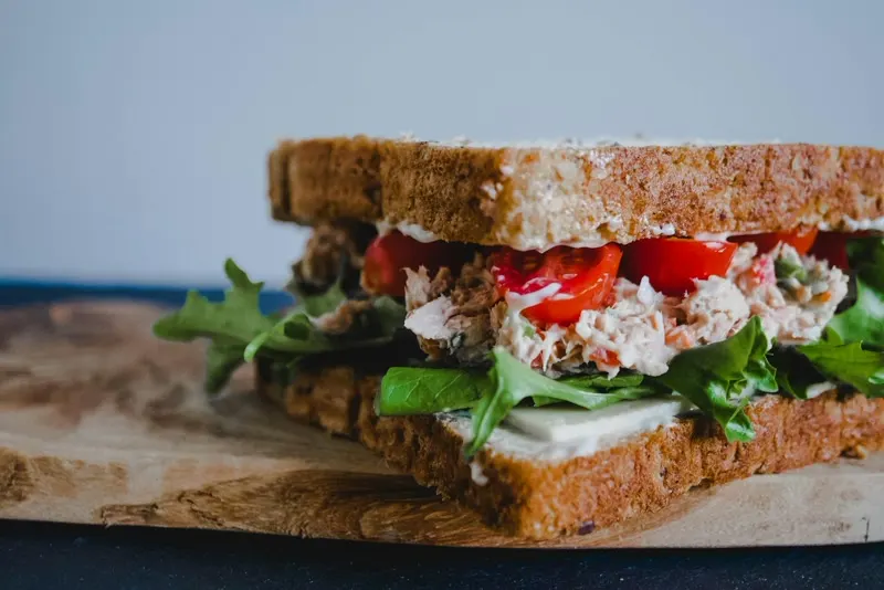 A tuna salad sandwich with tomato and greens